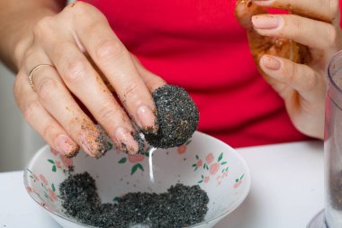 Bir kadın elinde kurutulmuş meyve şekeri tutuyor. Kuru erik, hurma ve hindistan cevizi topları. Bir tutam siyah susam tozuyla.