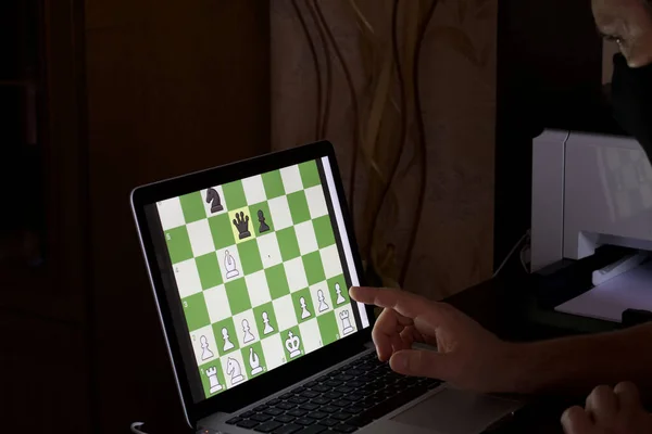 Man playing chess against computer Stock Photo