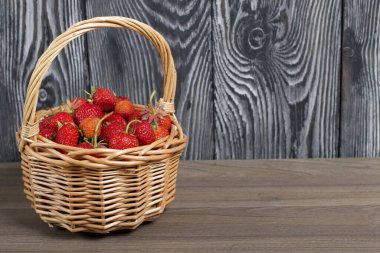 Hasır sepette olgun kırmızı çilekler. Beyaz ve siyaha boyanmış çam ağaçlarının arka planında. 2020 salgınında hasat.