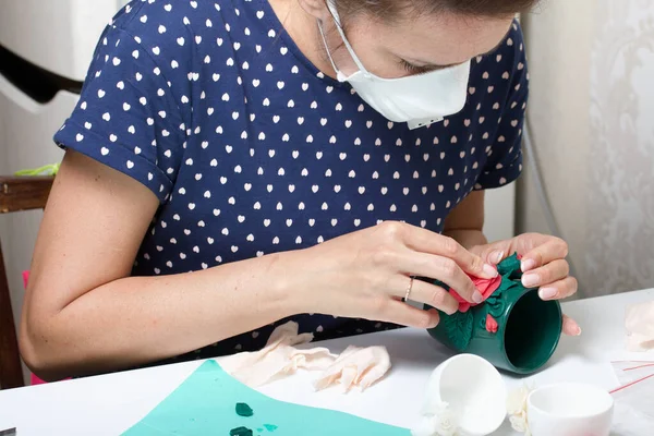 Woman glues polymer clay roses to a mug. Polymer clay of different colors. Crafts from polymer clay.