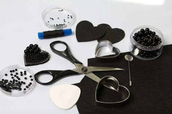 Crafts from beads. Materials for making brooches from black felt and beads.