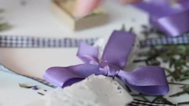 Bir kadın fiyonka bağlanmış bir kurdeleyle kibriti dağlıyor. Kurdeleyle bağlanmış bir buket. Yakın çekim..