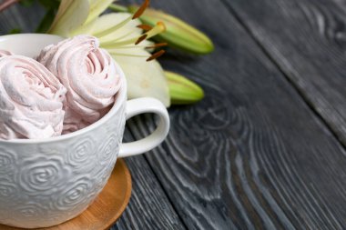 Çeşitli şekillerde ev yapımı zephyr. Bir kupada ve masanın yüzeyinde. Patlamamış tomurcukları olan bir zambağın yanında..