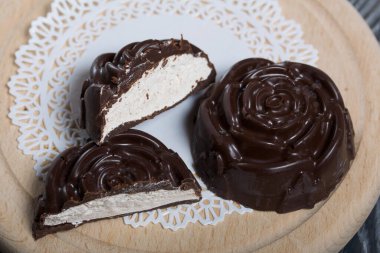 Gül şeklinde yapılmış bir çikolatalı marşmelov beyaz bir peçetenin üzerinde yatıyor. Bir lokum ikiye bölünür, bir dilim görünür..