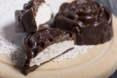 Gül şeklinde yapılmış bir çikolatalı marşmelov beyaz bir peçetenin üzerinde yatıyor. Bir lokum ikiye bölünür, bir dilim görünür. Yakın çekim..