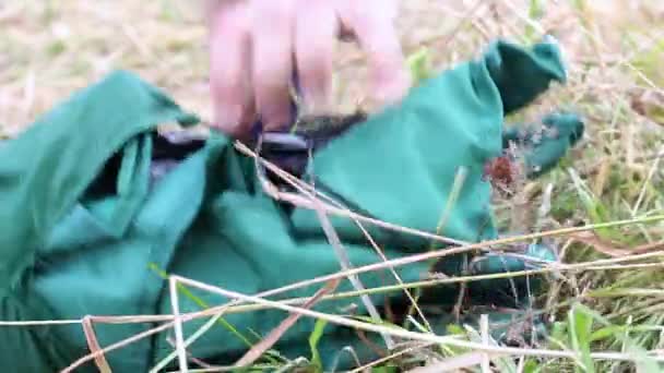 L'uomo rimuove il coperchio dalla sedia da campeggio piegata. Piano dettagliato. — Video Stock