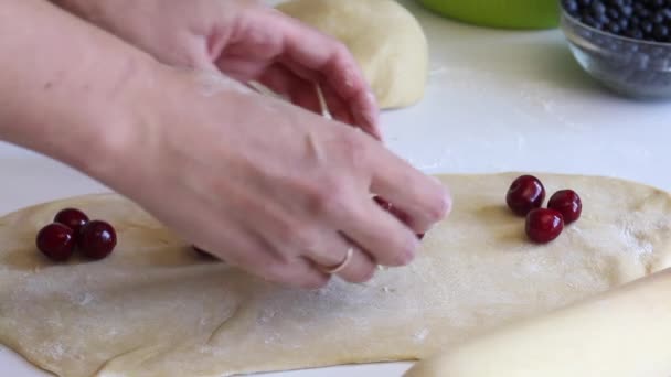 Eine Frau legt Kirschen auf den ausgerollten Teig. Knödel kochen. Nahaufnahme. — Stockvideo