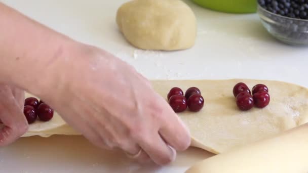 Žena balí třešně do těsta, které leží na rolovaném těstě. Vařím knedlíky. Detailní záběr. — Stock video