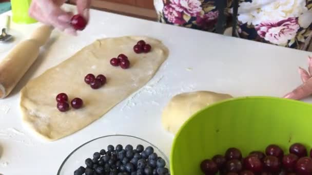 Una donna mette le ciliegie sulla pasta arrotolata. Gnocchi da cucina — Video Stock