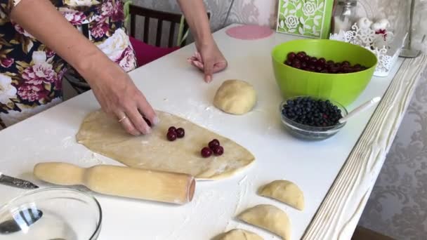 Una donna mette le ciliegie sulla pasta arrotolata. Gnocchi da cucina. — Video Stock