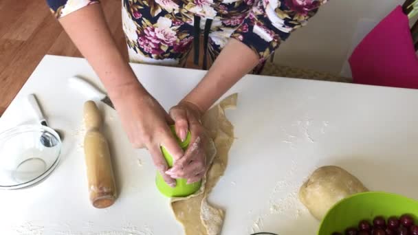 En kvinna formar dumplings med ett glas. Extraherar den form som krävs i degen. Dumplingar med blåbär och körsbär. — Stockvideo