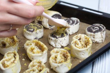 Bir kadın haşhaş ve cevizle doldurulmuş buklelere yumurta sürer. Pişirmek için..