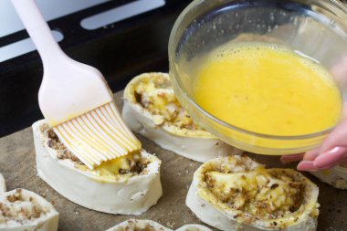 Bir kadın haşhaş ve cevizle doldurulmuş buklelere yumurta sürer. Pişirmek için..