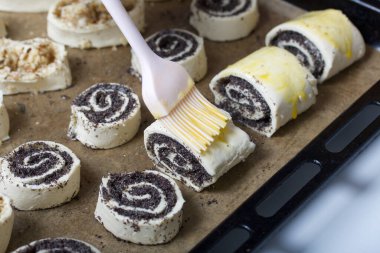 Bir kadın haşhaş ve cevizle doldurulmuş buklelere yumurta sürer. Pişirmek için..