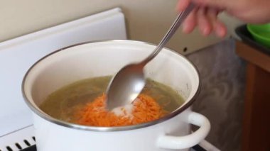 Bir adam tavuk çorbasını sebzelerle karıştırır. Sorrel çorbası tencerede kaynatılır. Bölgesel gıda.