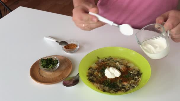 Muž položí na stůl talíř polévky. Přidá do něj zakysanou smetanu a odebere vzorek. Regionální potraviny. — Stock video