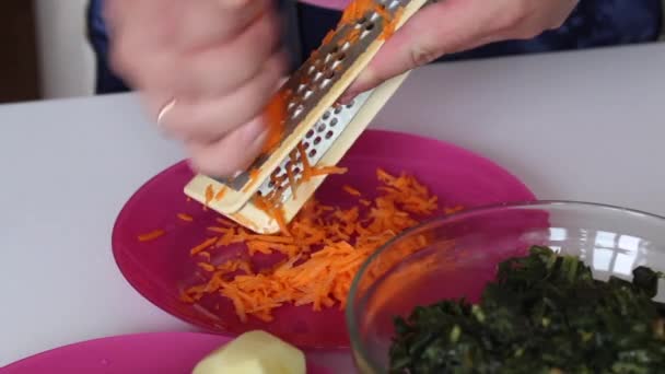 Un hombre está cortando zanahorias en un plato. Muy cerca hay papas y acedera. Para hacer sopa de acedera. Comida regional. Primer plano de disparo — Vídeo de stock