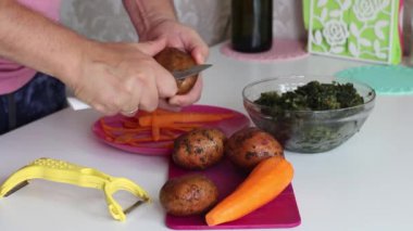 Adam patates soyuyor. Yakınlarda havuç ve kuş var. Kuş çorbası yapmak için. Bölgesel gıda.