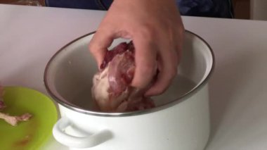 Bir adam donmuş tavuğu bir tencere suya koyar. Kuş çorbası yapmak için. Yakın çekim..