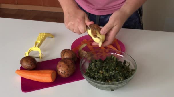 El hombre está limpiando la olla. A continuación en la mesa están las zanahorias y el acedera. Para hacer sopa de acedera . — Vídeo de stock