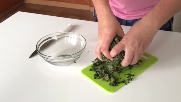 Ein Mann legt zerkleinerten gefrorenen Sauerampfer in ein Glasgefäß. Zur Zubereitung von Sauerampfersuppe. Nahaufnahme. — Stockvideo