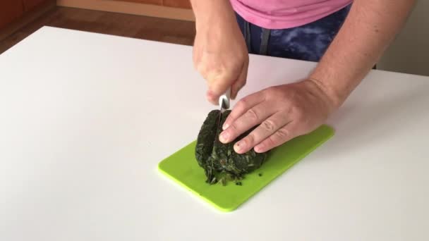 A man cuts frozen sorrel on a cutting board. For making sorrel soup. Close-up shot. — Stock Video