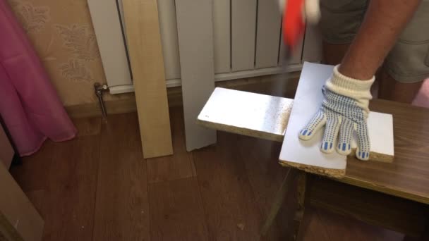 Un hombre está aserrando una tabla con una sierra. Hacer muebles en casa.. — Vídeo de stock