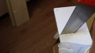 Bir adam demir testeresiyle tahtayı kesiyor. İşyeri numarasını kalemle işaretliyor. Evde mobilya yapmak.