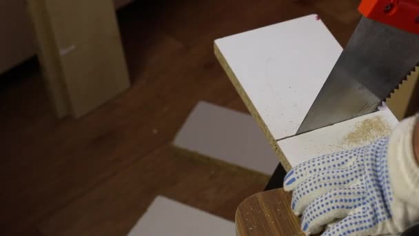 Making furniture at home. A man cuts a board with a hacksaw along the marked line — Stock Video