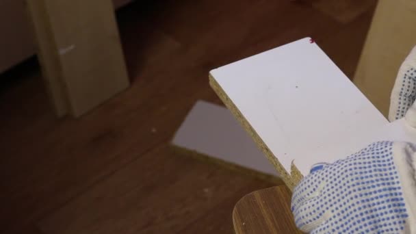 Un homme scie une planche avec une scie à métaux. Scies le long d'un guide de garniture. Fabrication de meubles à la maison.. — Video