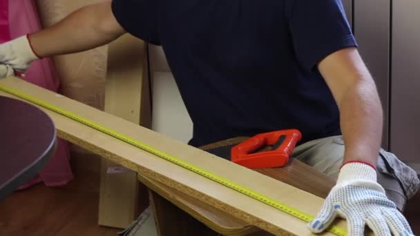En man mäter en bräda med ett måttband. Att göra möbler hemma — Stockvideo
