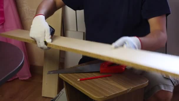 Un hombre mide una tabla con una cinta métrica. Hacer muebles en casa. — Vídeos de Stock