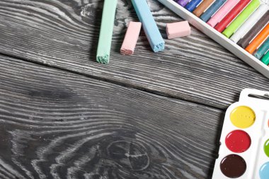 Farklı renklerde tebeşir, suluboya ve çizim için pastel boya. Siyah çam ağaçlarında.