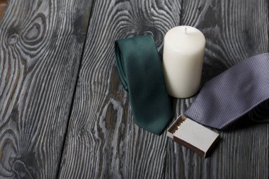 Bir erkek kravatı ve büyük beyaz bir mum. Bir kutu kibritin yanında. Aşk ve Birliktelik Nesneleri. Boyalı tahtalarda.