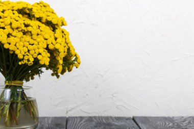 Cam bir kadehte bir buket tansi. Beyaz bir arkaplanda.