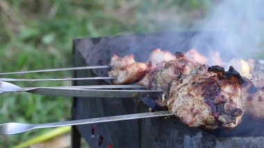 Izgaranın üstünde şiş kebap var. Kızarmış et ve sebzeler şişlerde görülebilir. Kadın şişleri ayarlar ve kebabı suyla doldurur..