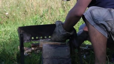 Bir adam metal elementlerden Brezilya biberi toplar. Bağların yan yüzeyleri. Barbekü çayırdaki çimlerin arasında duruyor. Yakın çekim..