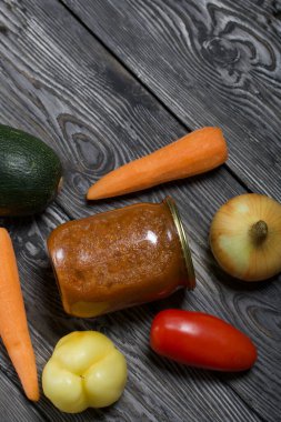 Kavanozda konserve kabak havyarı. Masanın yüzeyinde sebzeler, yemek pişirmek için malzemeler var..