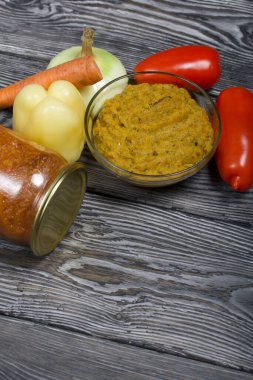 Yeni hazırlanmış kabak havyarı bir kabın içinde. Yanında, kavanozda konserve kabak havyarı. Masanın yüzeyinde sebzeler, yemek pişirmek için malzemeler..