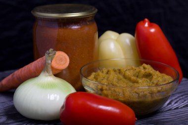 Yeni hazırlanmış kabak havyarı bir kabın içinde. Yanında, kavanozda konserve kabak havyarı. Masanın yüzeyinde sebzeler, yemek pişirmek için malzemeler..