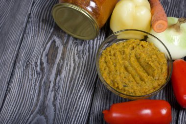 Yeni hazırlanmış kabak havyarı bir kabın içinde. Yanında, kavanozda konserve kabak havyarı. Masanın yüzeyinde sebzeler, yemek pişirmek için malzemeler..