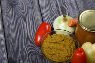 Yeni hazırlanmış kabak havyarı bir kabın içinde. Yanında, kavanozda konserve kabak havyarı. Masanın yüzeyinde sebzeler, yemek pişirmek için malzemeler..