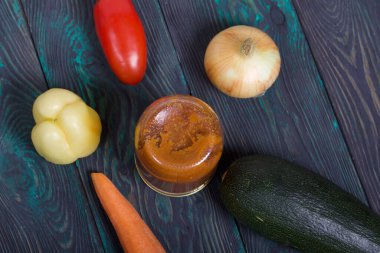 Kavanozda konserve kabak havyarı. Masanın yüzeyinde sebzeler, yemek pişirmek için malzemeler var..