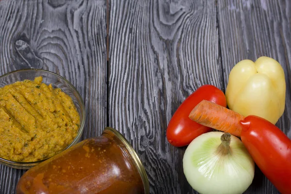 Yeni hazırlanmış kabak havyarı bir kabın içinde. Yanında, kavanozda konserve kabak havyarı. Masanın yüzeyinde sebzeler, yemek pişirmek için malzemeler..