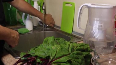 Bir adam mutfaktaki musluğu açar. Marul yapraklarını yıka. Lavabonun yanında pancar yaprakları var..