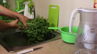 Bir adam mutfak musluğunun altında bir sürü maydanoz yıkıyor. Şiddetle suyu silkeliyor ve uzaklara götürüyor..