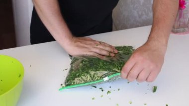 Adam vakum torbasını ezilmiş maydanozla dolduruyor ve içindeki havayı sıkıyor. Donmak için yeşiller.