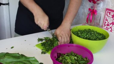 Adamın biri şeker pancarının tepelerini bıçakla kesiyor. Yanında ezilmiş maydanoz ve ezilmiş pancar yapraklarıyla dolu bir kap var..