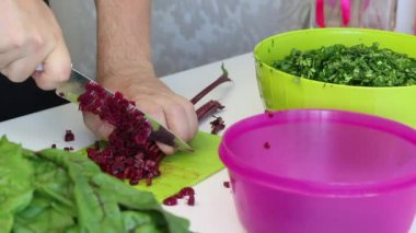 Adam pancarın tepelerini bıçakla kesip bir kaba koyuyor. Yanında doğranmış maydanozlu konteynır var..