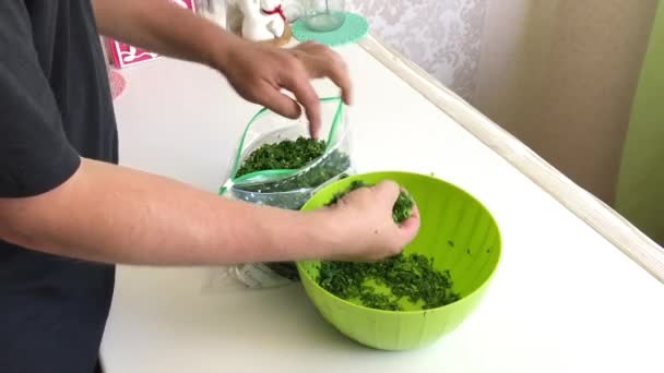 The man fills a vacuum bag with crushed parsley and squeezes the air out of it. Greens for freezing. Taken on the right. — Stock Video